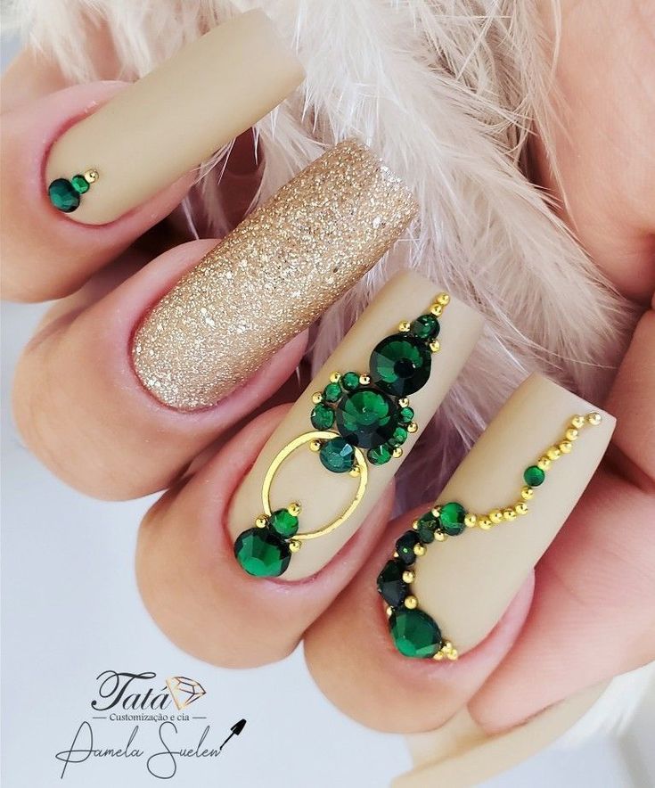 Glamorous Matte Nude and Sparkling Gold Nail Design with Intricate Green Gemstone Accents.