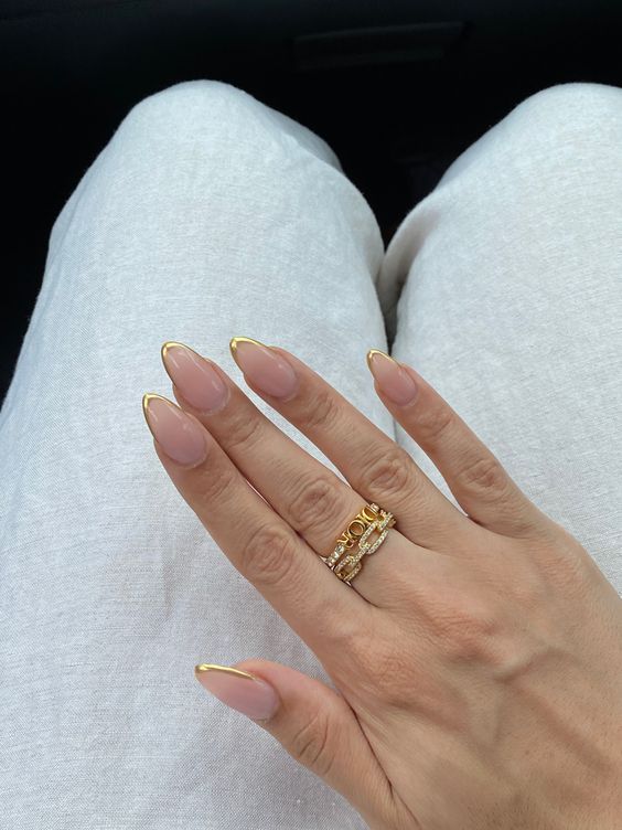 Sophisticated Almond-Shaped Nails with Chic Gold Tips and Delicate Accent Ring.