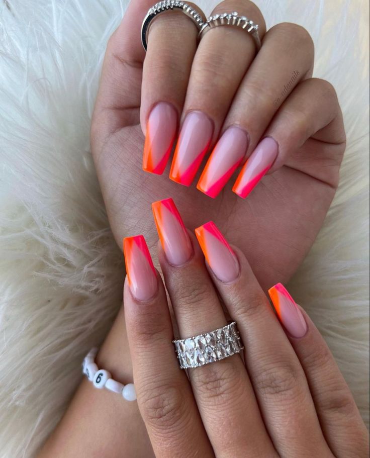 Striking Stiletto Nail Design with Bright Orange-Pink Ombre on a Nude Base.