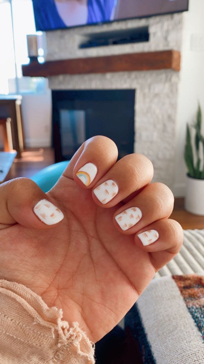 Whimsical Nail Design: White Polish with Colorful Accents and Gold Patterns