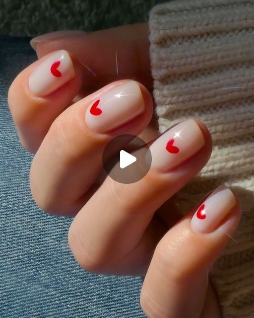 Charming Soft Nude Nail Design with Playful Red Heart Accents for a Romantic Touch.