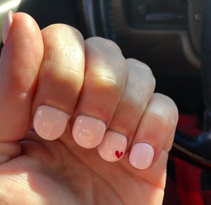 Elegant Pastel Pink Nails with Glossy Finish and Charming Red Heart Accent.