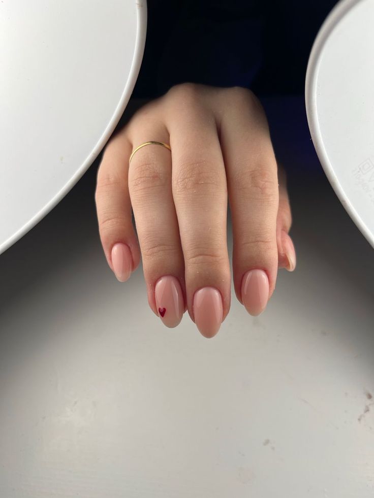 Elegant Nude Nails with Subtle Heart Design for a Charming Touch.