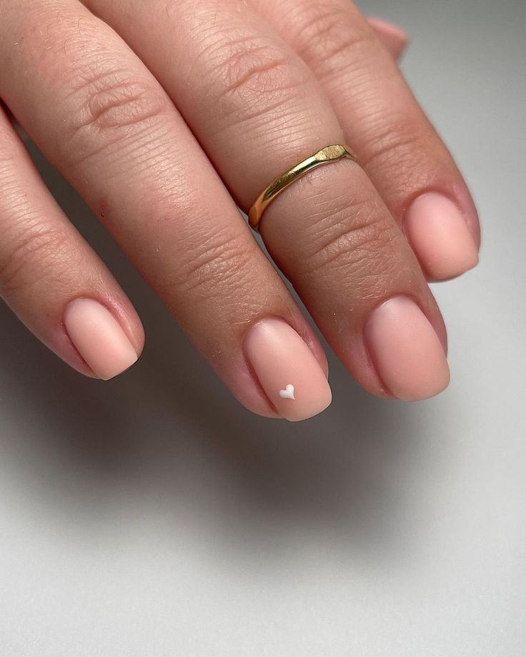 Elegant Soft Matte Nude Nail Design with White Heart Accent: A Minimalist Touch for Any Occasion.