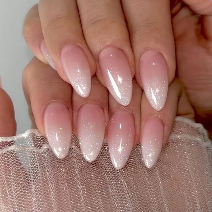 Elegant Ombre Nails: Soft Nude Base Transitioning to Sparkling White Tips with Subtle Glitter.