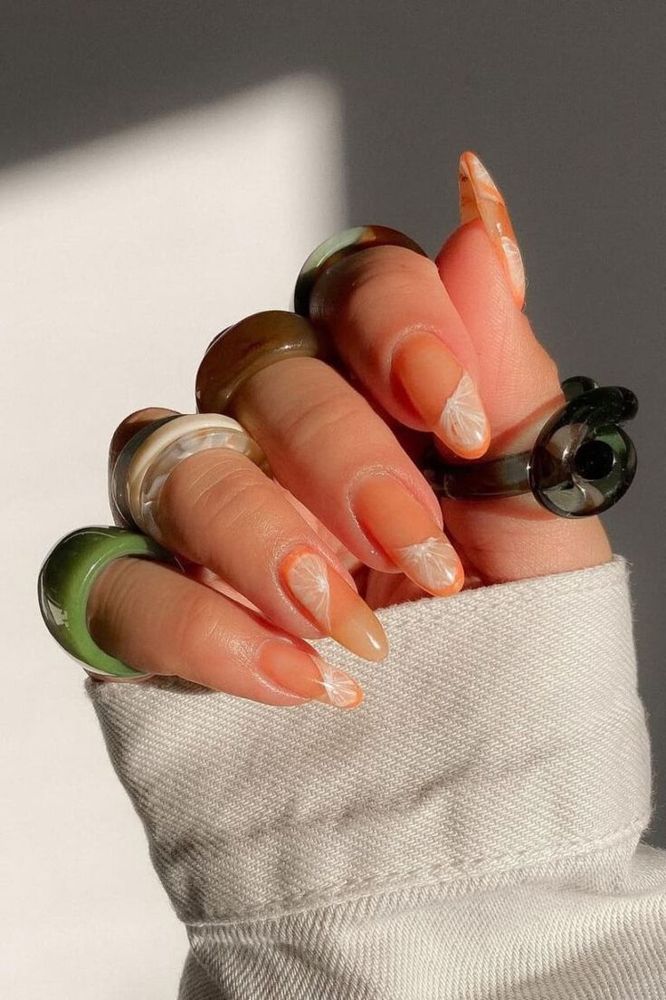 Chic Nail Design with Elegant Tips and Swirl Pattern Enhanced by Oversized Rings and Warm Lighting.