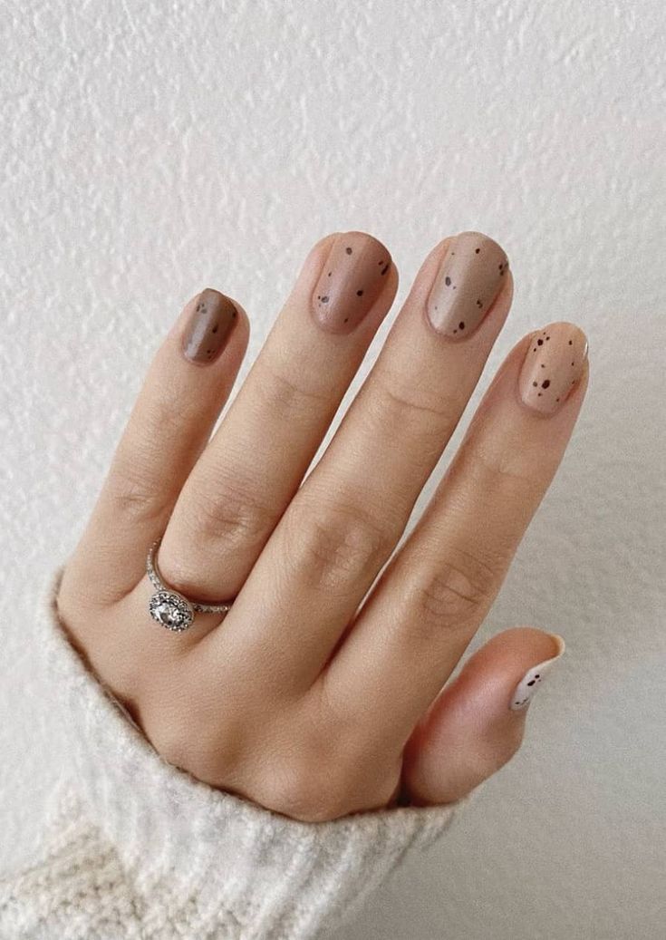 Chic Nail Design with Muted Beige and Taupe Palette Accentuated by Delicate Black Speckles.