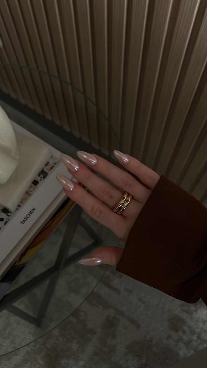 Sophisticated Almond-Shaped Nails with Nude Polish and Gold Ring Accent.