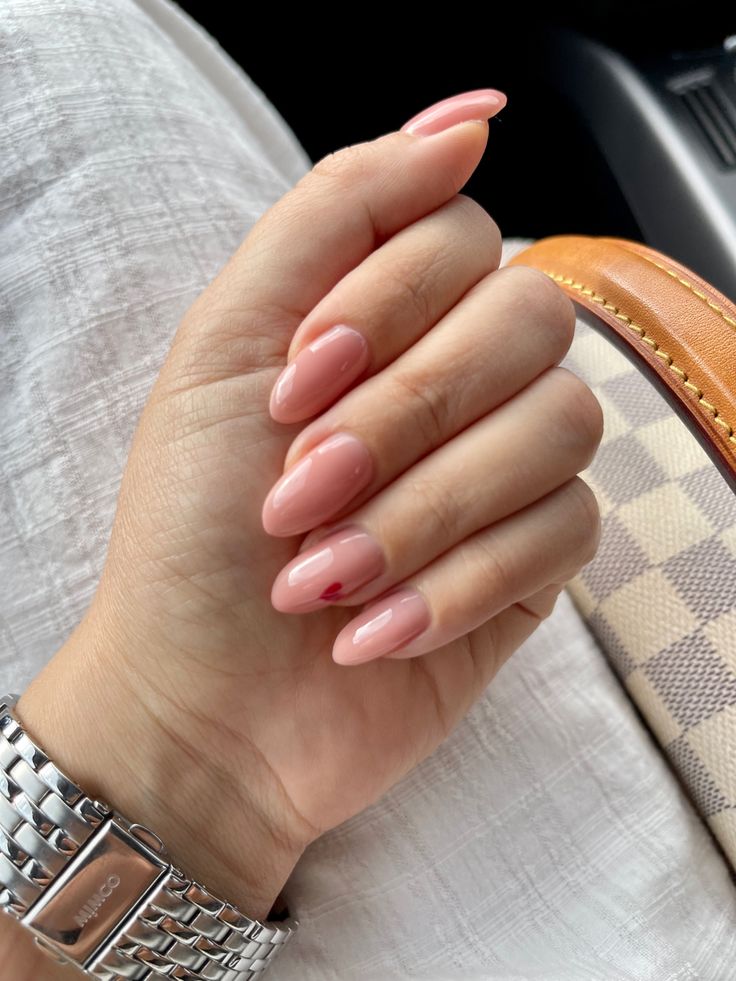 Sophisticated Almond-Shaped Nails with Nude Pink Polish and Playful Red Accent.