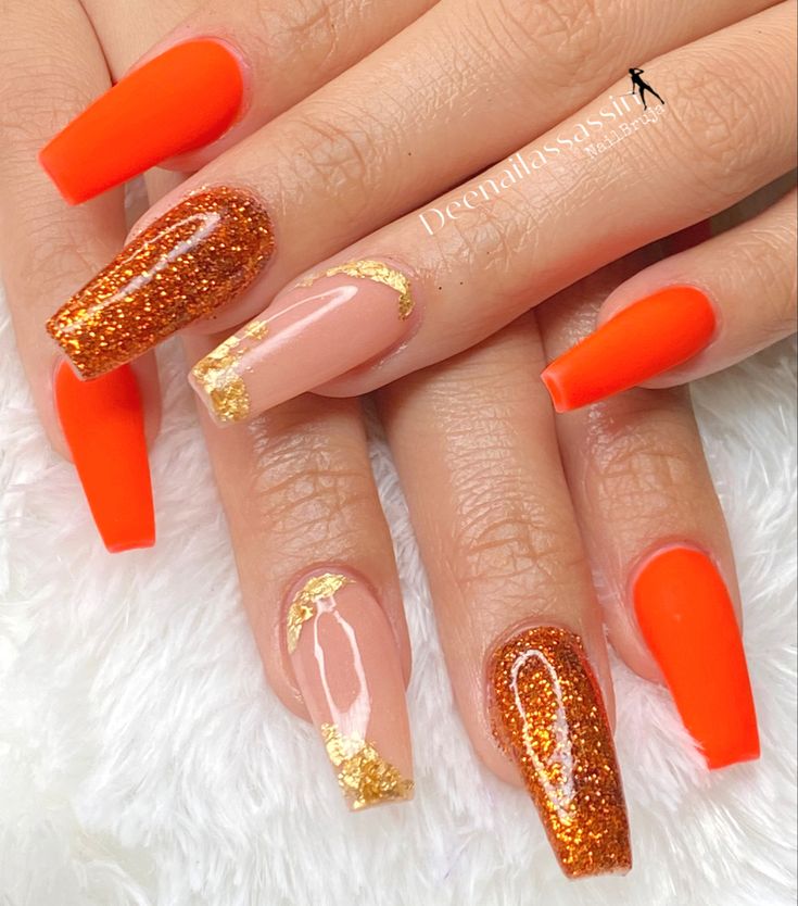 Bold Orange Nail Design with Geometric Patterns and Sparkling Accents.