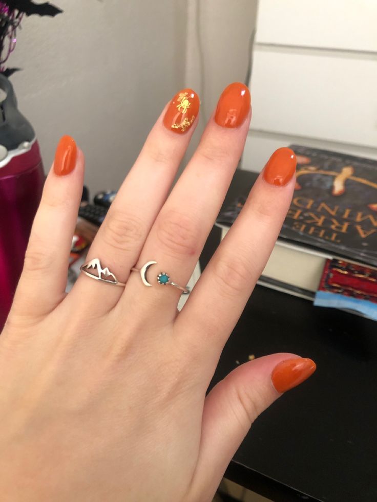 Bold Orange Nail Design with Elegant Gold Accent and Minimalist Rings.