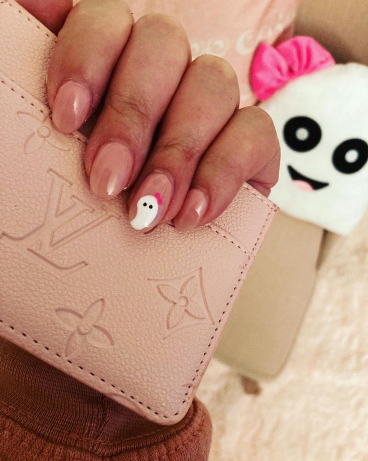 Elegant Nude Nail Design with Playful Ghost Accent and Pink Bow.