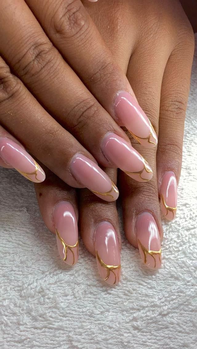 Chic Almond-Shaped Nail Design: Soft Pink Base with Delicate Gold Accents.