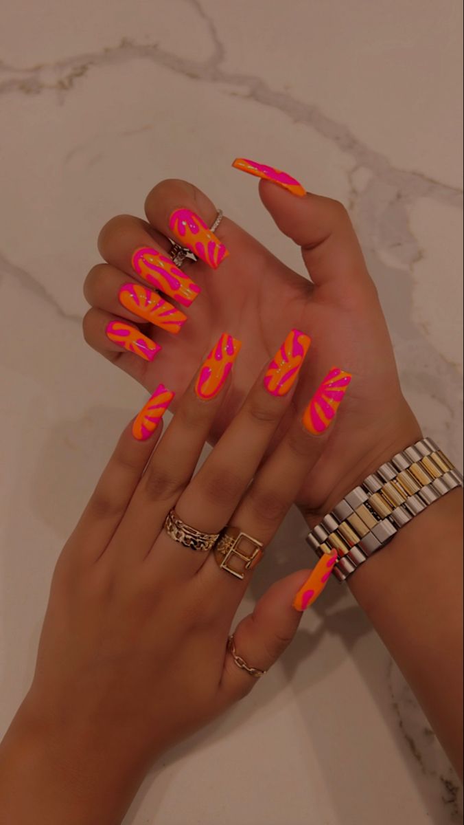 Bold Neon Nail Design with Playful Pink and Orange Swirls Enhanced by Chic Gold and Silver Accessories.