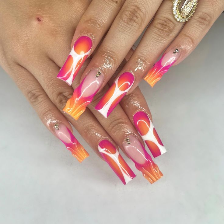 Striking Vibrant Nail Design with Pink, Orange Hues and Glamorous Gem Accents.