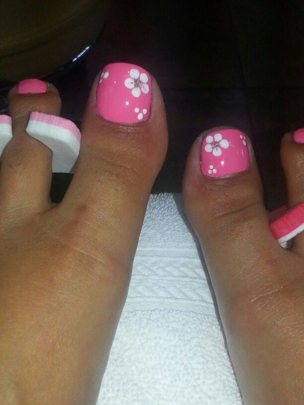 Playful Bright Pink Toenails with Delicate White Floral Patterns for a Charming Summer Look