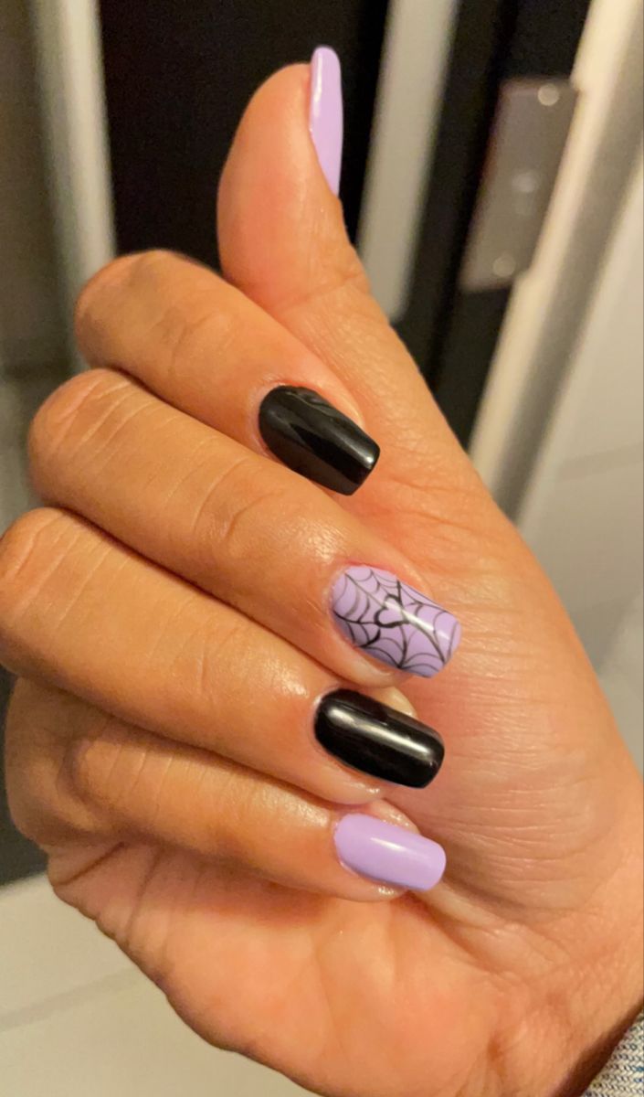 Playful Halloween Nail Design: Black and Pastel Lavender with Spiderweb Accent.