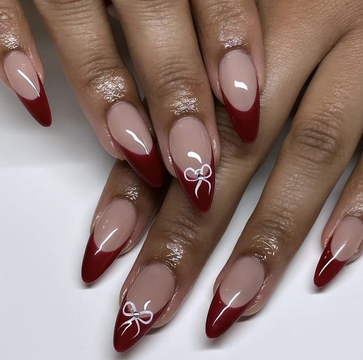 Sophisticated Nail Design: Nude and Deep Red with Delicate White Bows.