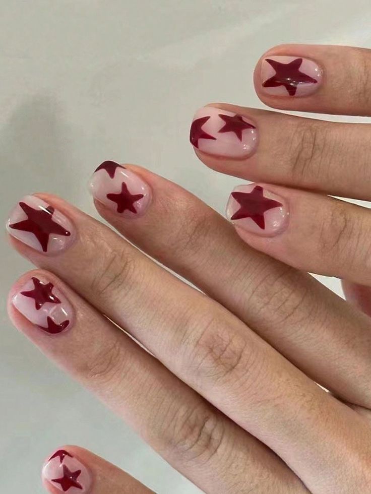 Playful Star-Themed Nail Design: Bold Red Stars on Nude Base.