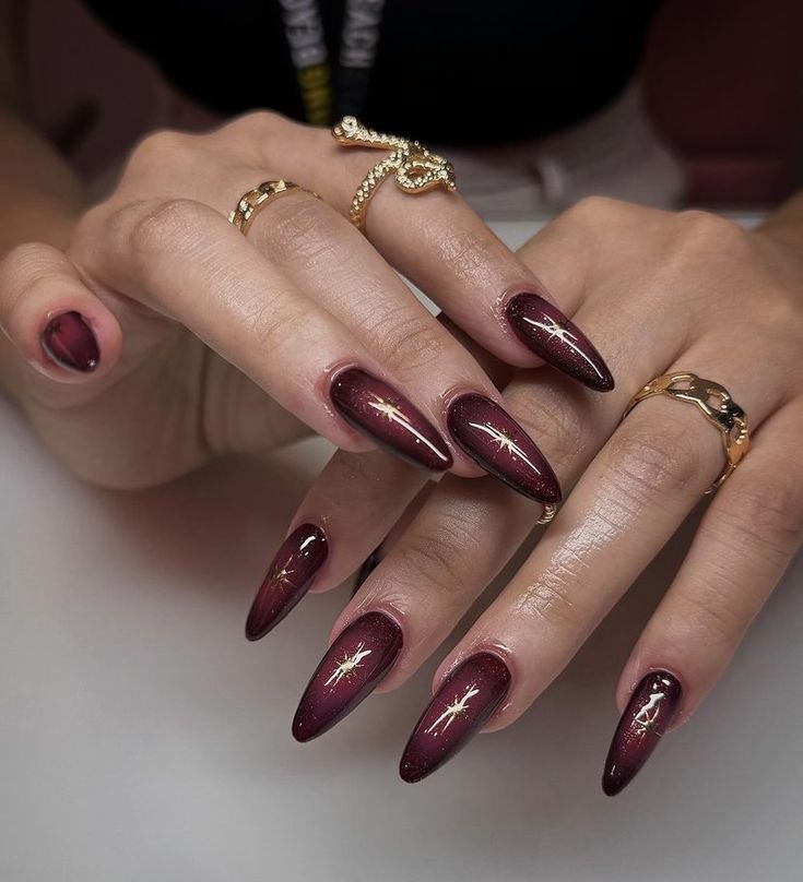 Striking Almond-Shaped Nails with Deep Burgundy Gradient and Elegant Gold Accents.