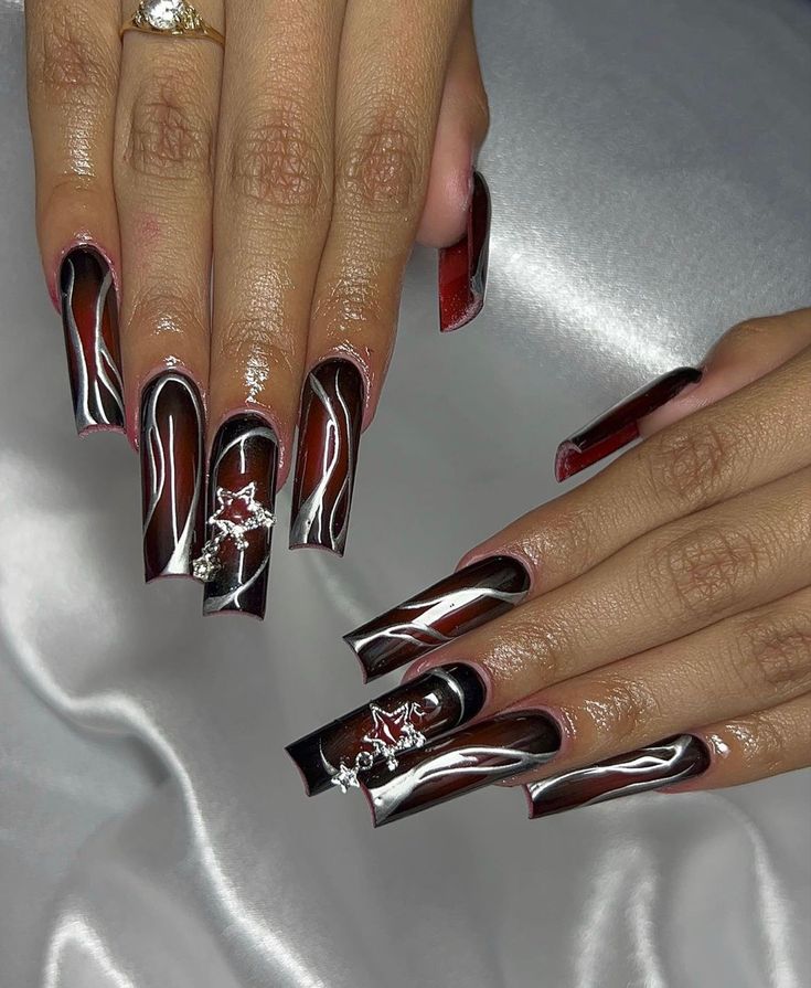 Striking Red and Black Swirl Nail Design with Glamorous Star Embellishments and Glossy Finish.