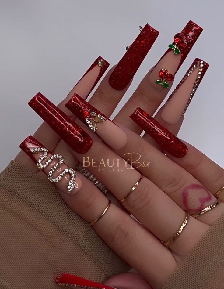 Glamorous Red Nail Design with Glossy and Glitter Finishes, Enhanced by Gems and Floral Accents.