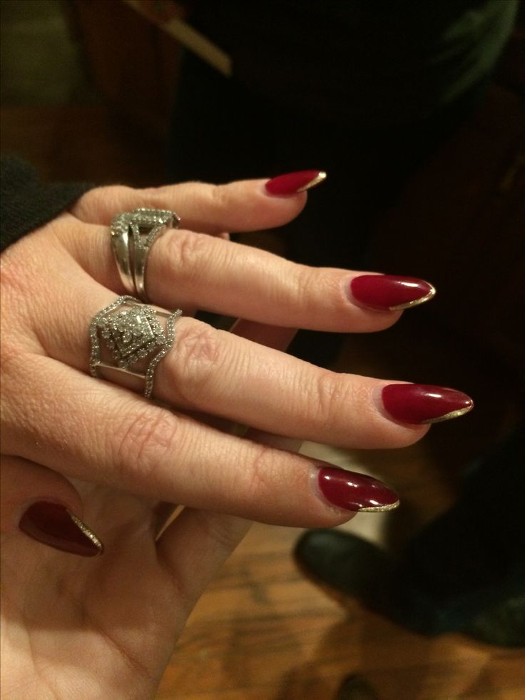 Chic Red Manicure: Long Pointed Nails with Glamorous Silver Rings for Sophisticated Style.