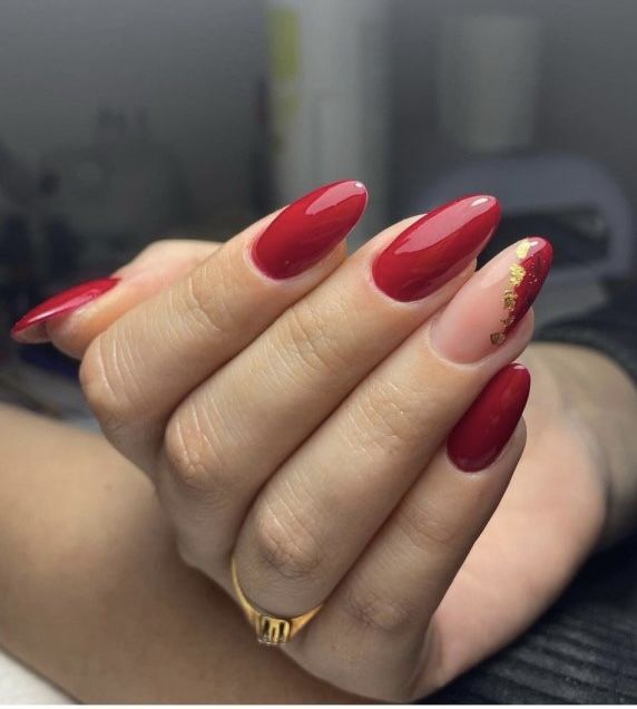 Elegant Glossy Red Nail Design with Textured Accents and Gold Detailing.