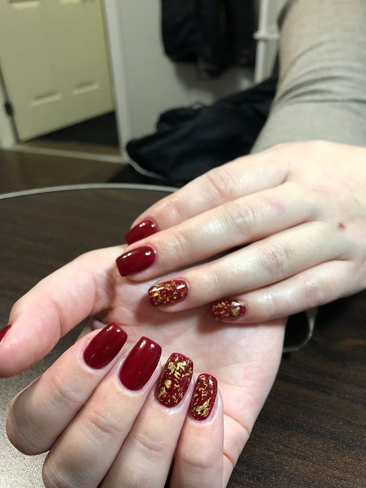 Sophisticated Deep Red Nail Design with Glamorous Gold Accents.