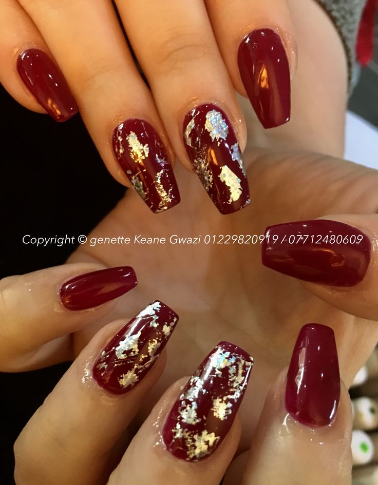 Elegant Glossy Burgundy Nails with Glamorous Metallic Accents and Gold Leaf Detailing.