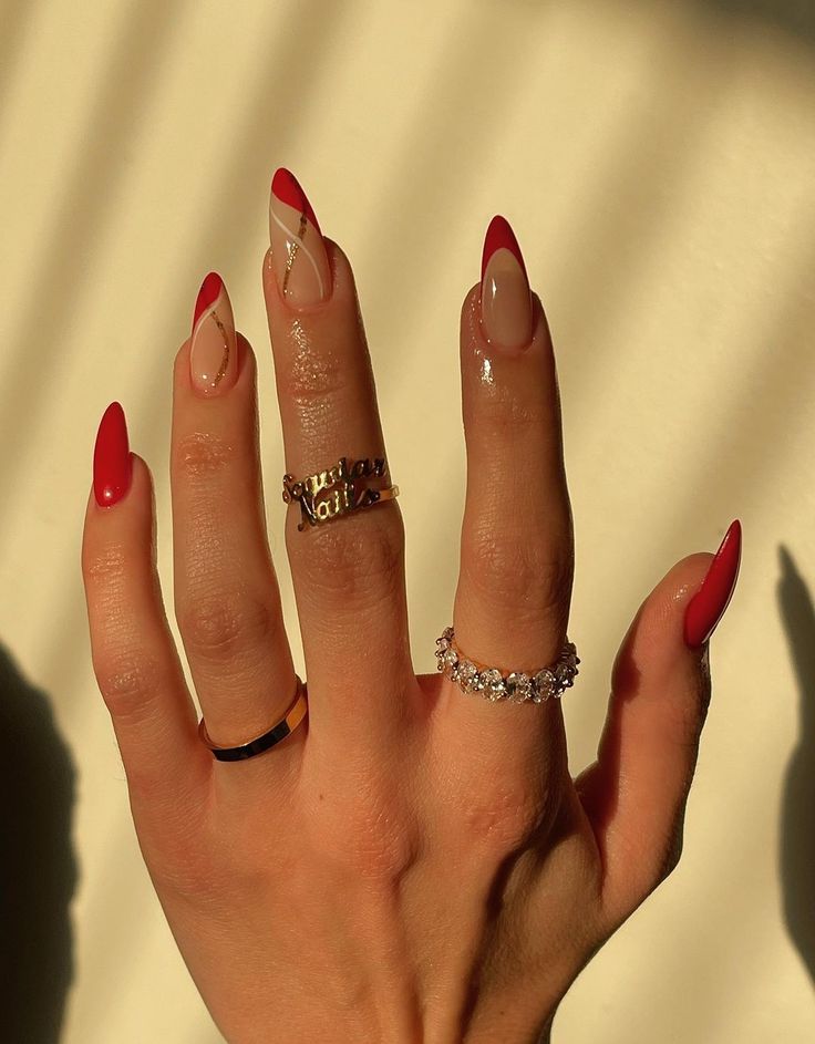 Chic Red-Tipped Almond Nail Design with Nude Base and Delicate Rings.