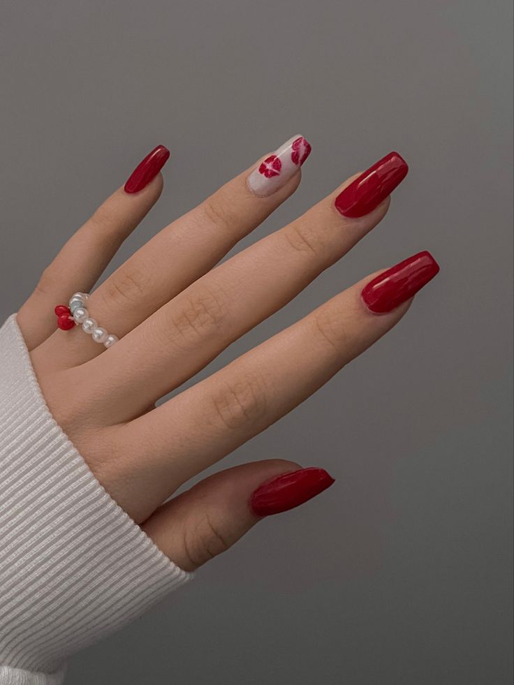 Chic Red Nail Design with Glossy Finish and Floral Accent.