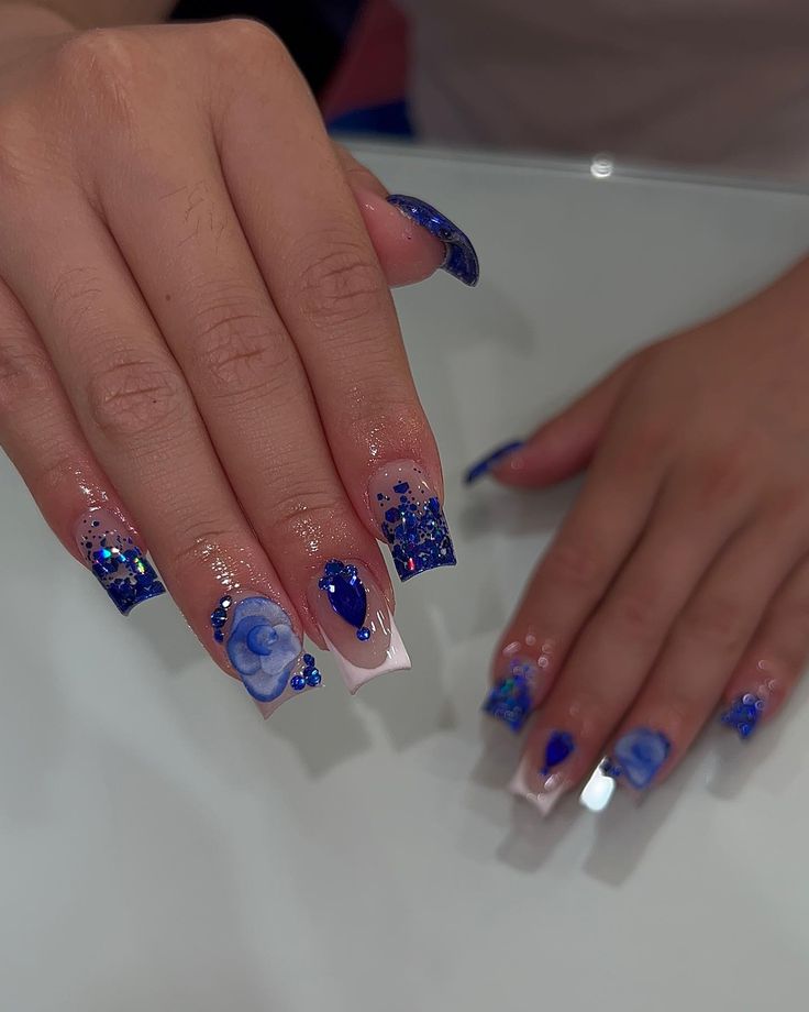 Vibrant Blue Floral Glitter Nail Design with Elegant Shape.