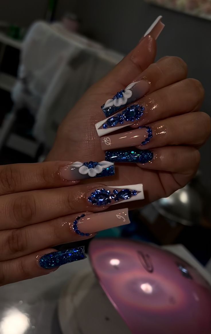 Elegant Glittery Blue and White Nail Art with Floral Accents and Mixed Finishes.