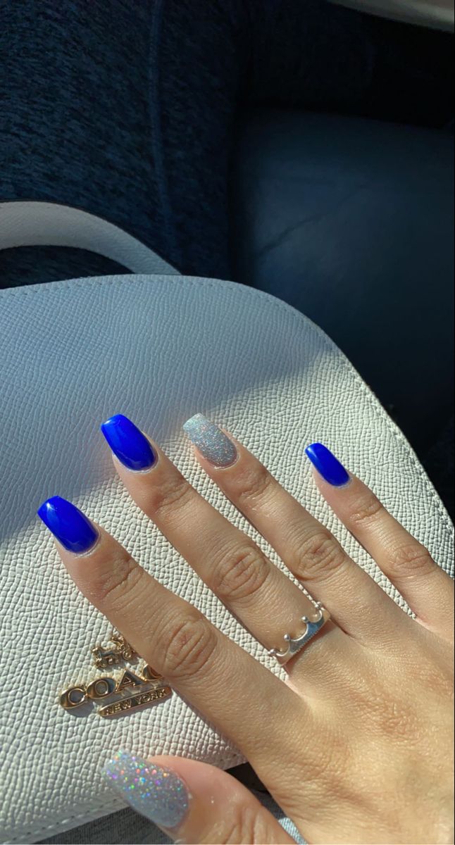 Striking Contrast: Bold Blue Nails with Shimmering Silver Tips and Subtle Glitter Accents.