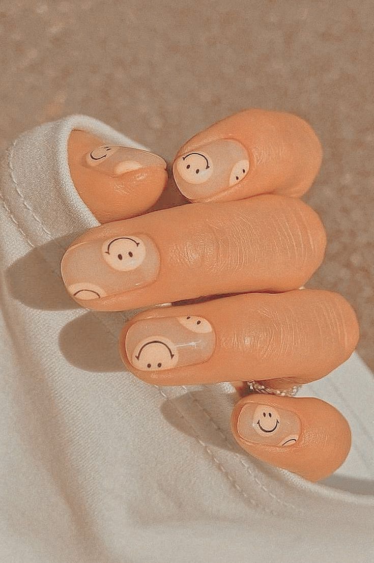 Playful Peachy Nail Design with Smiley Faces and Moon Motifs.