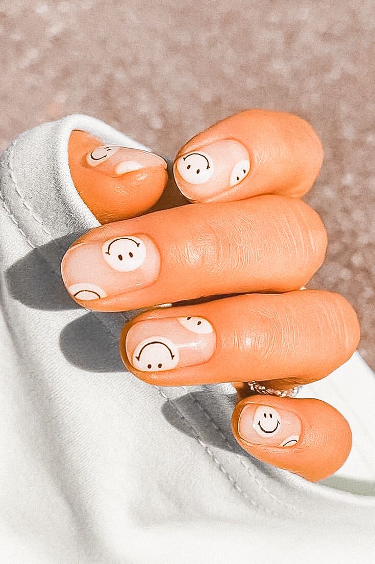 Cheerful Smiley Face Nail Art on Soft Peach Base for a Whimsical Look.