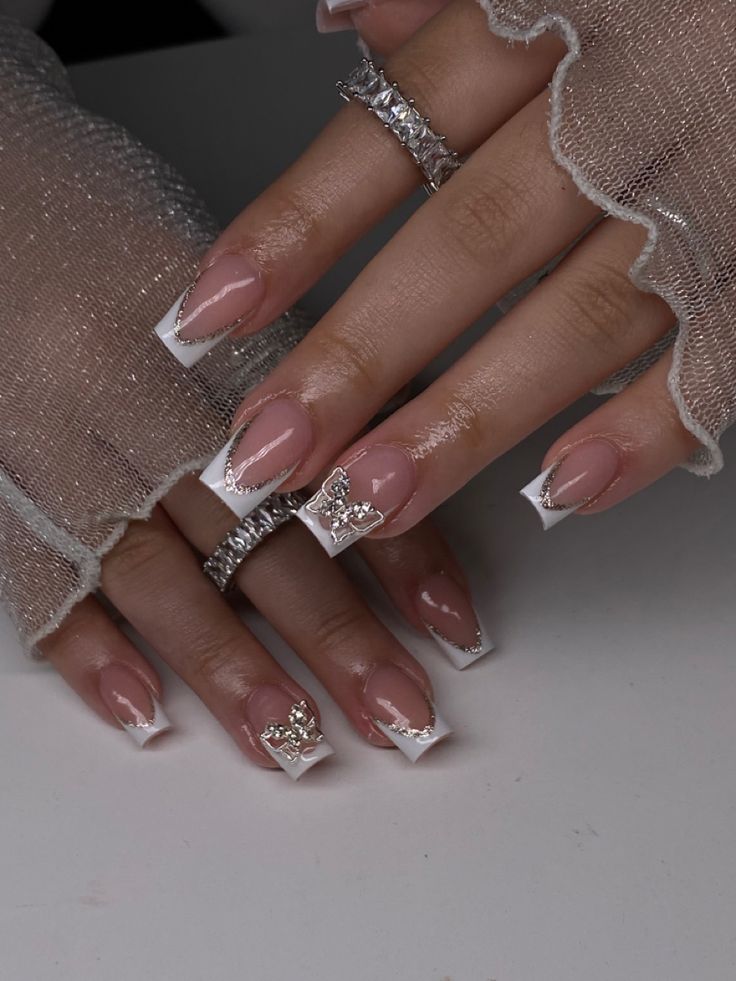 Sophisticated Beige French Tip Nails with Silver Embellishments and Delicate Rings.