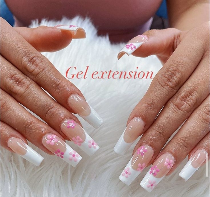 Chic Nude and White Gel Nail Extensions with Floral Accents: A Playful French Manicure.