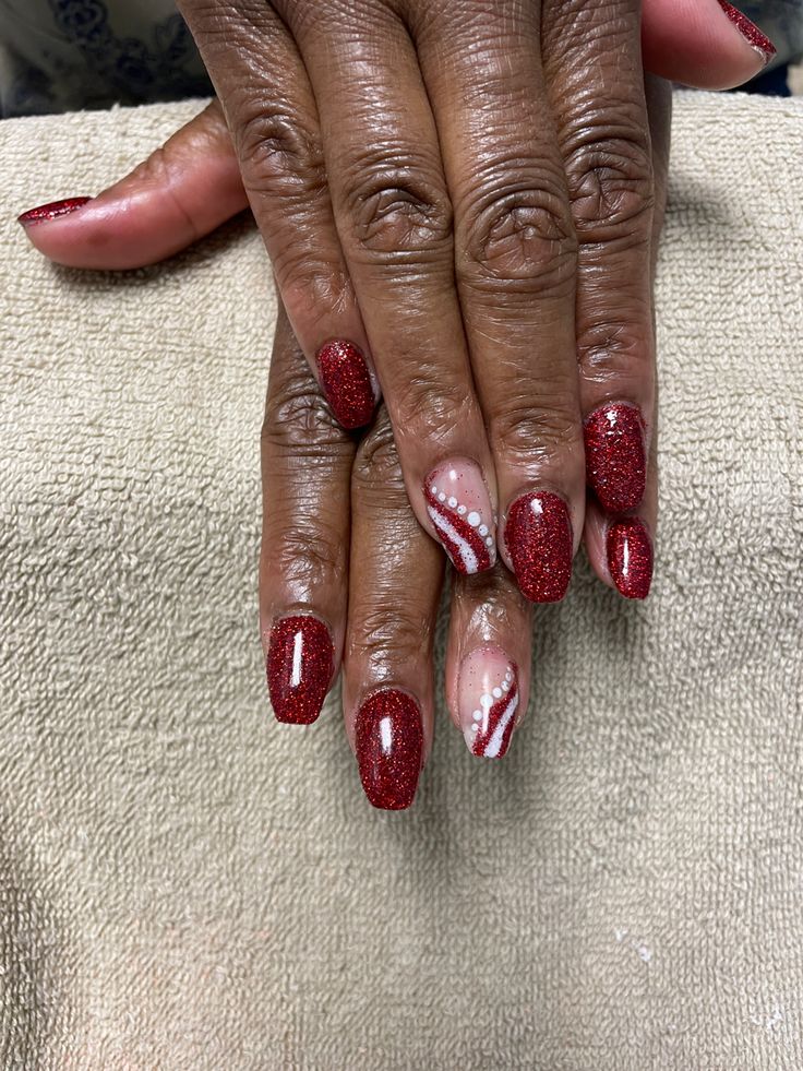 Sophisticated Red Nail Design with Glitter, Gloss, and Intricate White Detailing