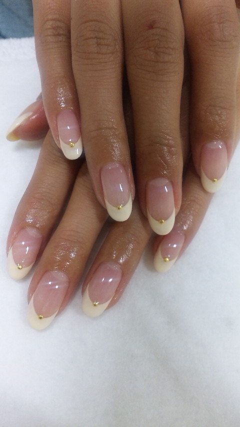 Sophisticated Nude and White Tip Nail Design with Gold Embellishments.