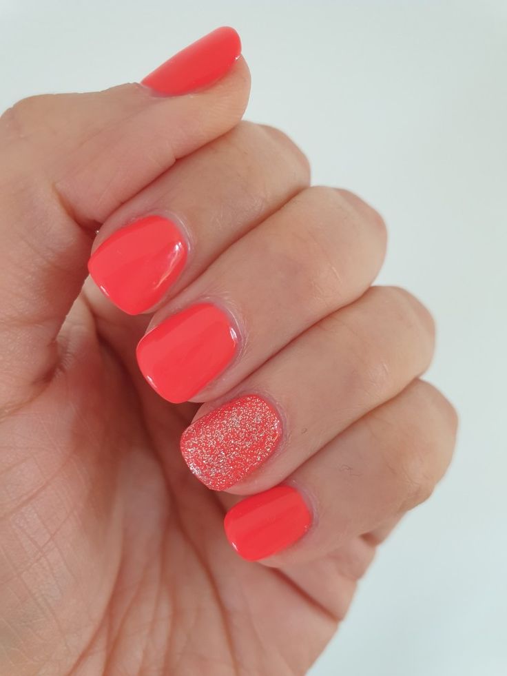 Playful Coral Nail Design with Glossy Finish and Sparkling Glitter Accent.