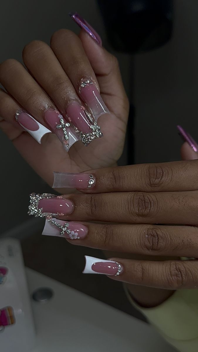 Chic Glamorous Nail Design: Soft Pink and White Tips with Rhinestones and Embellishments.