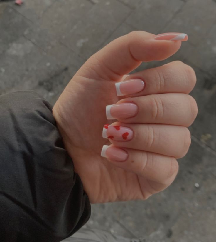 Chic French Manicure with Fun Red Heart Accents for Romantic Occasions.