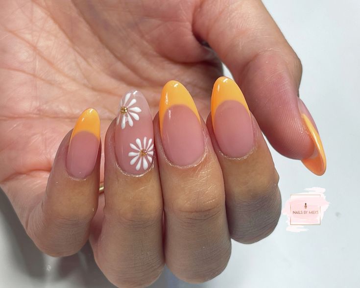 Cheerful Yellow-Orange French Tips with Elegant Floral Accent for a Playful Look.