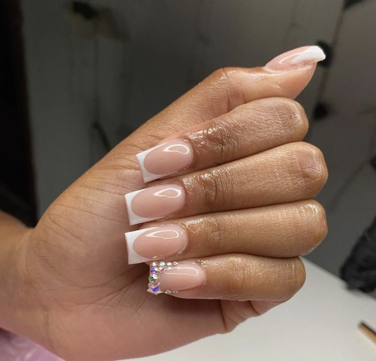 Elegant French Tip Nails with Glossy Nude Base and Sparkling Gem Accent.