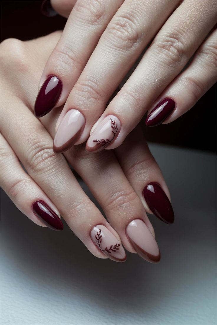 Chic Almond-Shaped Nail Design: Deep Burgundy and Nude Tones with Floral Accent.