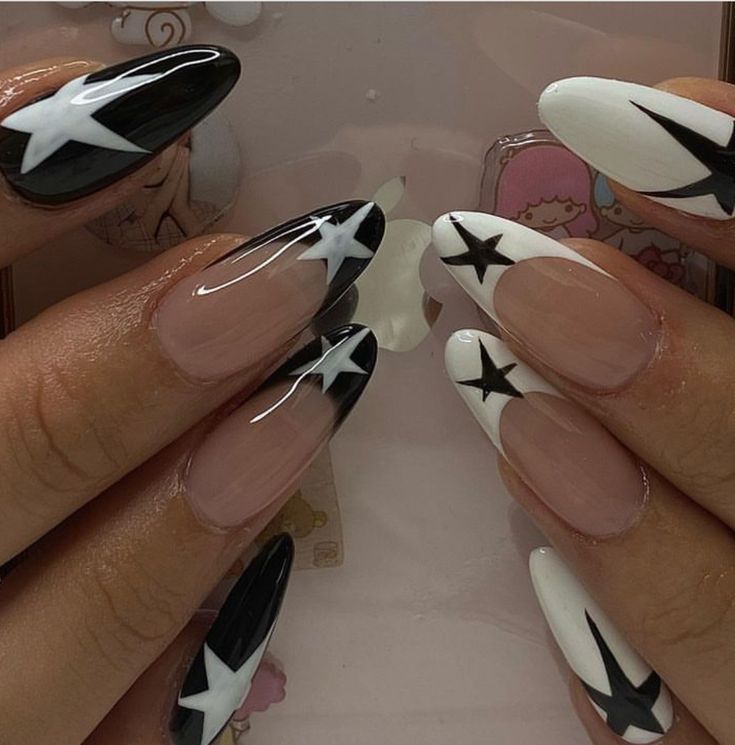 Elegant Black and White Almond Nail Design with Bold Star Motifs and Varied Finishes.