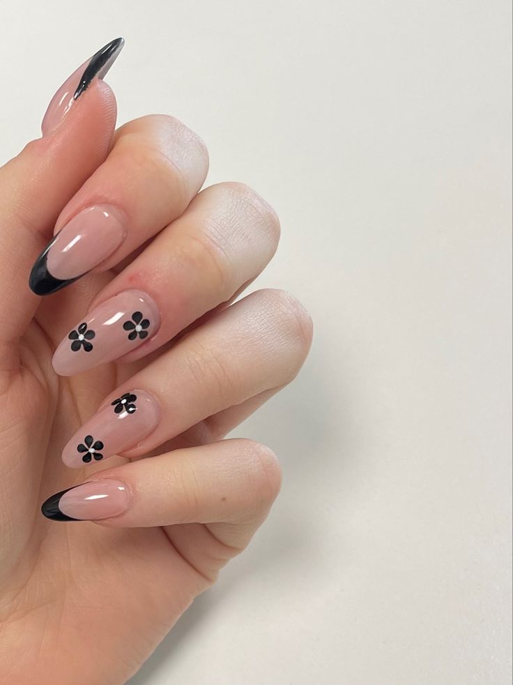 Chic Elegant Nail Design: Soft Nude Base with Bold Black Tips and Floral Accents