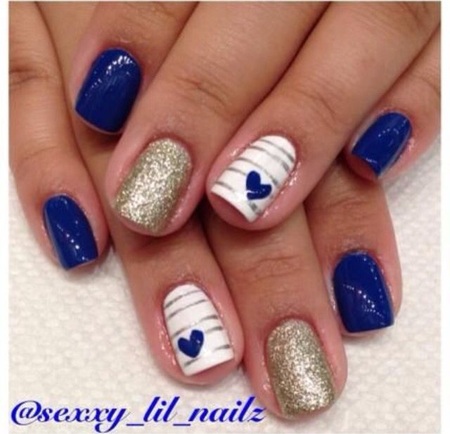 Chic Deep Blue and Gold Nail Design with White Accents and Playful Patterns.